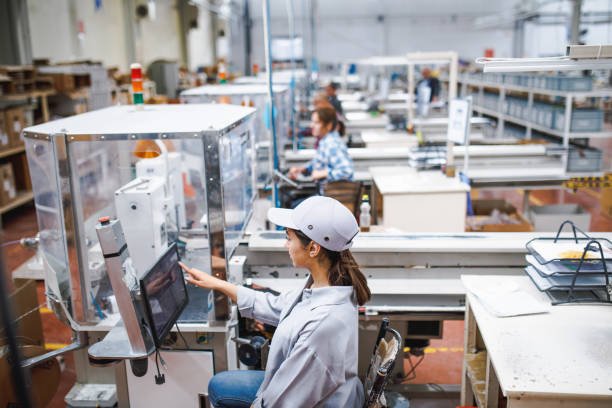 Professional young industrial factory woman employee working with machine parts putting, checking and testing industrial equipments cables in large Electric electronics wire and cable manufacturing plant factory warehouse